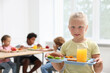 © New Africa - Little girl with tray of tasty food in school canteen