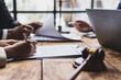 © Wasan - Lawyers and clients reviewing contract agreement terms before signing. Business partners carefully review contract terms before signing at a wooden table.