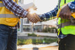 © Wasan - Construction workers shaking hands at construction site, agreement and partnership in a project.