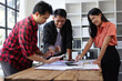© Wasan - Startup business team analyzing documents at meeting table. Young entrepreneurs are reviewing documents and discussing business strategy during a meeting in a modern office space.