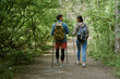 © AnnaStills - Young adult Caucasian man and young adult Caucasian woman hiking together on forest trail, carrying backpacks and using trekking poles, walking side by side and talking outdoors
