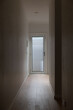 © AuthorLinyt - Narrow indoor hallway with wooden flooring leading to frosted glass door, softly lit with minimalist white walls and modern clean design