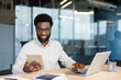 © Liubomir - Man working at desk with laptop and tablet in modern office