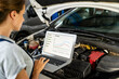 © Barillo Images - Female auto mechanic using laptop to inspect vehicle in workshop. Car performance graphs.