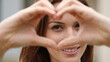 © Viktor_D - Hands framing a heart shape in front of smiling woman’s face.