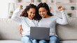 © Prostock-studio - Excited african american mother and daughter sitting on couch with laptop, looking at gadget screen, raising fists up and screaming, happy black mom and kid playing video games at home
