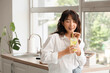 © Pixel-Shot - Young Asian woman drinking citrus infused water in kitchen