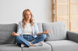 © Pixel-Shot - Beautiful blonde woman in headphones meditating on sofa at home