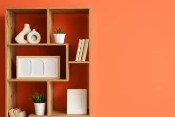 Poster - bookshelf with blank frames and plants near orange wall