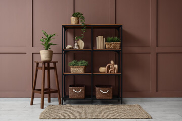 Poster - bookshelf with wicker baskets and plants near brown wall in room