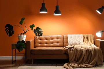 Wall Mural - Interior of living room with brown sofa, palm plant and glowing lamps