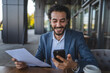 © Miljan Živković - Happy businessman reading documents and using smart phone in outdoor cafe