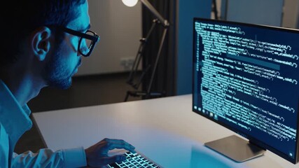 Focused programmer working on code in a dark room with blue lighting in the evening hours