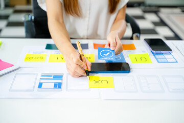 Creative UX UI designer working on app wireframe layout with sticky notes and color palette. web design, app development