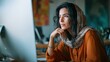 © MakoPoko - Thoughtful woman with scarf working on computer in modern workspace