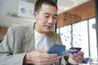 © Charlie's - Asian Man paying with credit card on smart phone at office. Male Using Smartphone for Shopping electronic wallet Online