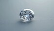 © Viktor - Loose round brilliant cut diamond rests on gray textured surface. Faceted gemstone displays sparkle, shine with clear white brilliance. Luxury item represents investment, engagement, wedding jewelry.