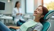 © Viktor - Asian woman smiles happily in modern dental chair. Dentist in background, bright clean clinic creates comfort, trust. Peaceful appointment shows client satisfaction, excellent dental care, wellness.