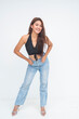 © Mdv Edwards - Confident young Asian woman in black halter top and denim pants posing casually with hands in pockets. Isolated on a white background.