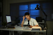 © Stella 16 - Asian young businessman eating noodles while working in office at night.