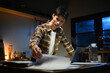 © Stella 16 - Asian man working with laptop and reading documents at home in kitchen. Man works with financial documents.
