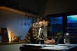© Stella 16 - Focused man working late at night on laptop in kitchen with coffee