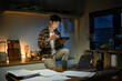 © Stella 16 - Young man sits in the kitchen at the bar counter works in tablet and drinks a coffee. Home atmosphere, work in the evening after a hard day. Home office.