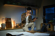 © Stella 16 - Young man sits in the kitchen at the bar counter works in tablet and drinks a coffee. Home atmosphere, work in the evening after a hard day. Home office.