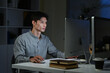 © Stella 16 - Staying late to get it done. Shot of a young businessman using a computer at his desk during a late night at work.