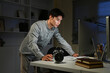 © Stella 16 - A man is stand at a desk at night with a computer and a keyboard. He is looking at the computer screen