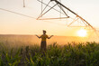 © Westend61 - Farmer standing in irrigated corn field at sunset with pivot system