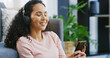 © peopleimages.com - Relax, headphones and smile with woman and phone for streaming service, calm audio and ambient sound. Guided podcast, white noise and peace playlist with person in living room of home for break