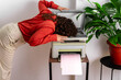 © VISTA by Westend61 - Office worker with head on photocopier experiencing burnout stress