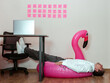 © VISTA by Westend61 - Businessman lying on inflatable flamingo under office desk with fatigue