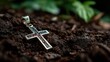 © Oleksandr - A silver cross pendant is on the ground. The pendant is surrounded by dirt and leaves
