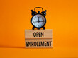 © Natallia - Open Enrollment symbol. Wooden blocks with words Open Enrollment. Beautiful orange background with alarm clock. Business and Open Enrollment concept. Copy space.