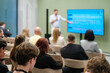 © Anton Gvozdikov - Audience attending a business seminar with speaker presenting on a screen in conference room.