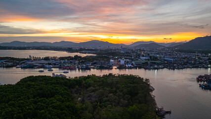 Wall Mural - Aerial view of Stunning sunset featuring fishing port in Phuket. The vibrant sky transitions from soft purples to fiery orange hues, creating a tranquil and picturesque atmosphere.