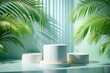 © Osama - Minimalist product display with three white cylindrical podiums surrounded by lush green palm leaves, casting dramatic shadows on a light blue background