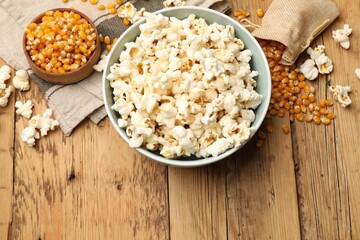 Wall Mural - Tasty popcorn and corn kernels on wooden table, flat lay. Space for text