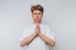 © bodnarphoto - Young man expressing concern and reflection with hands clasped together against a plain background