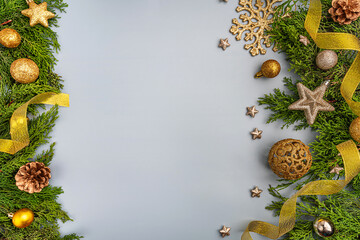 Wall Mural - festive golden ornaments, stars, and ribbons arranged with green foliage on a light blue backdrop fo
