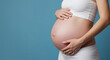 © Sunnn - Close-up of a pregnant woman on a solid background holding her belly with loving hands and copy space