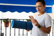 © Taras Grebinets - Woman Holding Yoga Mat and Phone on Balcony in Daylight
