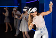 © JackF - Excited young girl in VR glasses interacting with immersive environment of virtual reality world, standing with controllers in hands and actively gesticulating while controlling objects in game .
