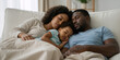 © Milan - Black family sleeping on the couch. African American parents and their toddler napping together at home.