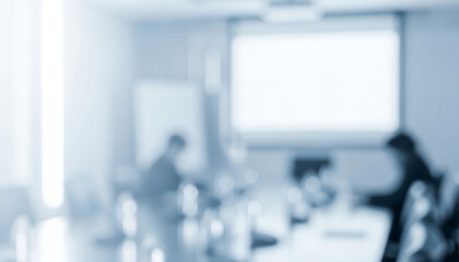 Blurred image of a conference room with people and a projection screen, resembling a classroom environment with learning interaction in a bright professional setting.