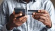 © Johannes - modern technology and online shopping african man in shirt paying for goods on internet using credit card and cell phone closeup of human hands holding plastic card and mobile selective focus no logo