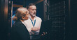 © peopleimages.com - Server room, talking and people on laptop for technical support, network maintenance and database. IT technicians, team and man with woman on computer for diagnostics, system update and cybersecurity