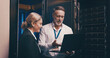 © peopleimages.com - Laptop, talking and team of engineers in server room for technical support, database or cybersecurity. Computer, collaboration and people with system upgrade in data center for network programming.